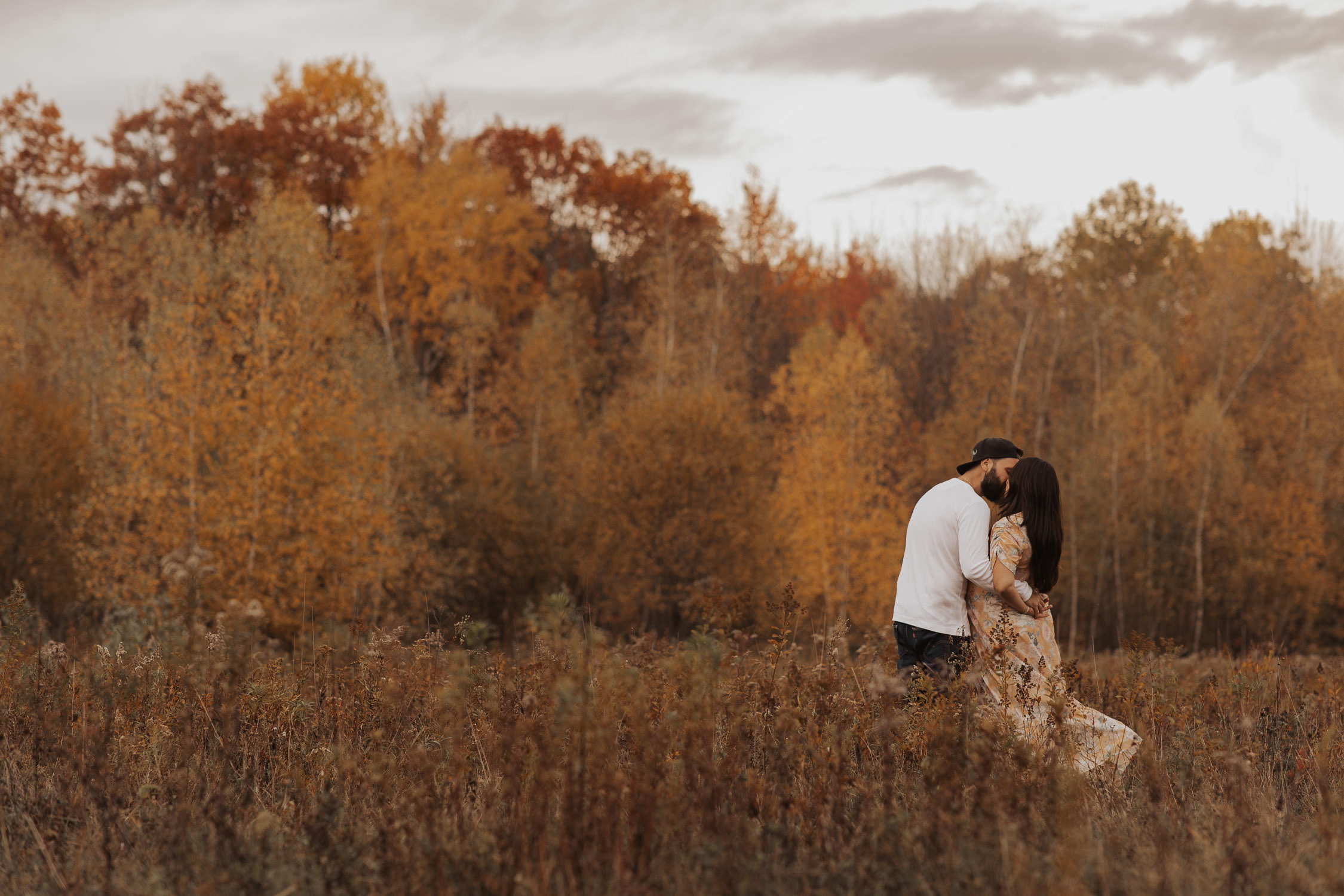 parents to be maternity photo session in a field surrounded with golden fall colours